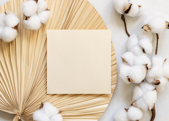 Blank card on dried palm leaf with cotton flowers top view, wedding mockup