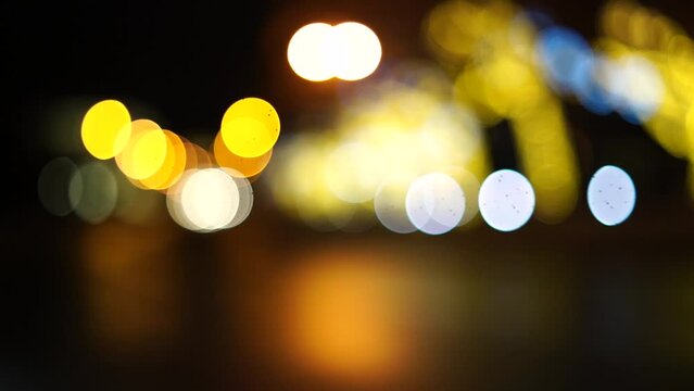 Blurred car lights bokeh in the evening city. Defocused headlights and street lighting at night. Moving bokeh circles of cars at night. Blurred city traffic background