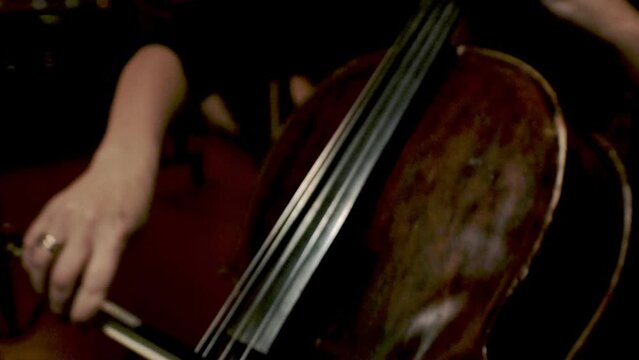 Playing music on cello. Female hands with bow performing classic symphony with string instrument. Professional cellist