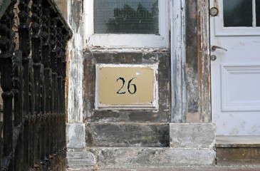 Worn Metal Sign with Number 26 on Entrance of Old Stone Building