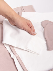 Woman holds cotton white jumpsuit bodysuit for baby on white background. Long sleeve