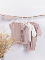 Set of clothes for a newborn baby on hangers on white background. Space for text