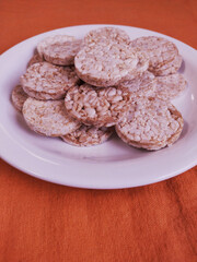 close up of plate with round rice cake Wholegrain at on 
orange background