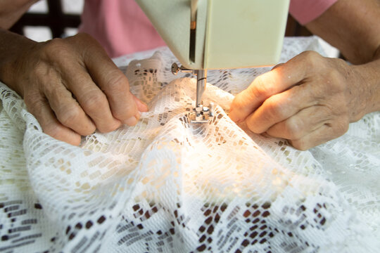 Close up brazilian elderly woman using sewing machine