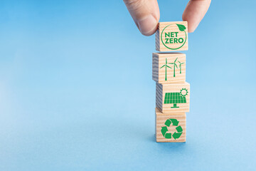 Net Zero and Carbon Neutral Concept. Hand putting wood block with Net Zero icon on top of others...