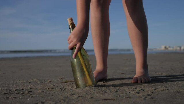 Girl finding a sea bottle with message in it