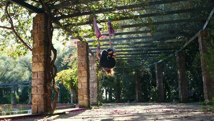 A woman throws off her shoes and climbs onto a yoga hammock in the garden