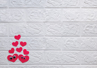 Couple in love. Space for text. Composition for valentines day in style paper art. Flat lay. Two heart-shaped faces with eyes surrounded by confetti hearts on brick wall background with copy space.