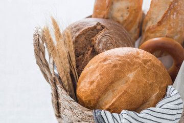 Assortment of fresh bread in a wicker basket close-up. Freshly baked bread on the table. The context of a bakery with delicious bread. Confectionery products.