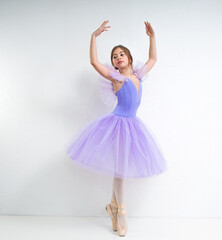 Fototapeta na wymiar Young ballerina in a purple dress on a white background.