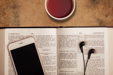 Open vintage old holy Bible book with phone