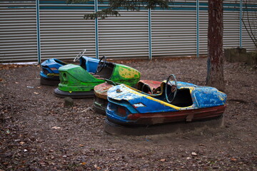 Old bumper cars with cracked paint in an abandoned amusement park