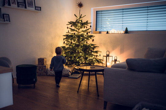 Kleinkind schaut sich den Weihnachtsbaum mit Geschenken an