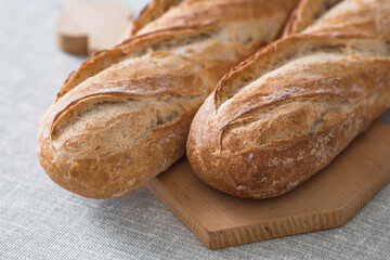Fresh delicious bread close-up. Freshly baked sourdough bread with a golden crust on a wooden board. The context of a bakery with delicious bread. Confectionery products.