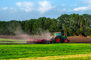 a tractor in the field cultivates land for sowing crops. High quality photo
