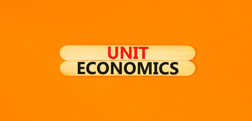 Unit economics symbol. Concept words Unit economics on wooden stick. Beautiful orange table orange background. Business and unit economics concept. Copy space.