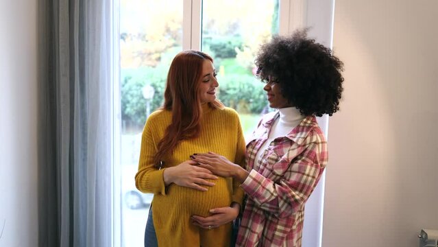 multiracial lesbian couple eagerly awaits the arrival of their child. The African American wife lovingly their love and excitement palpable