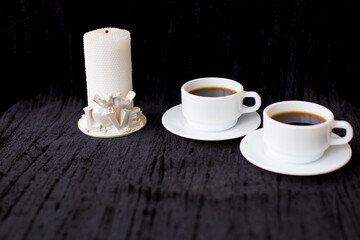 candle and two cups of coffee on a black background