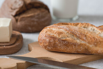 Fresh delicious bread close-up. Freshly baked sourdough bread with a golden crust on a wooden board. The context of a bakery with delicious bread. Confectionery products.