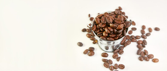 A metal bucket with a pile of scattered roasted coffee beans.
