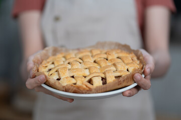 Smiling young woman chef cook in apron. Woman holding plate with delicious apple pie. apple pie...