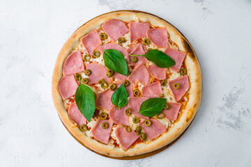 Pizza with ham, olives, basil and cheese top view