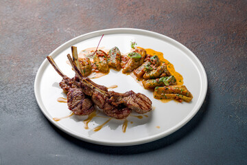 Rack of lamb with auberdine with sauce on white plate