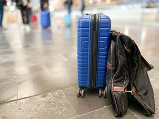 Naklejka na ściany i meble Blue suitcase and garment rack on the platform floor of a modern long-distance train station