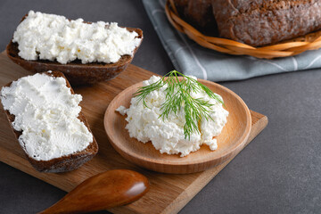 Fototapeta na wymiar Home made rye bread on a wooden cutting board with curd cheese, ricotta and dill