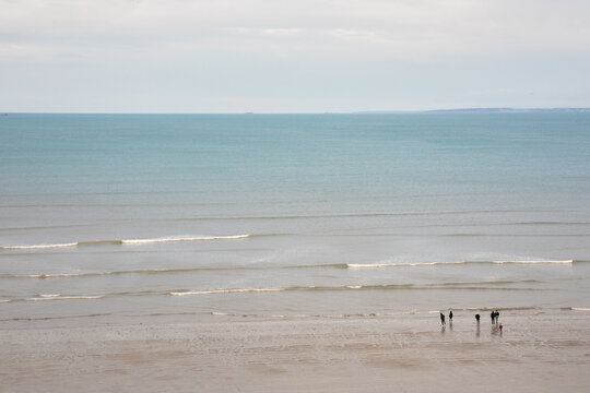 Des personnes se baladent sur une plage &agrave; Binic en Bretagne en hiver.