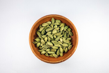 Green cardamom or cardamon or cardamum or green elaichi in earthen brown bowl isolated on white background. Top view. Close up