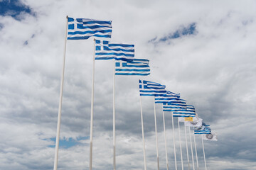Fluttering row of Greek flags in the beautiful white clouds