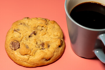 Gormet Chocolate ChipCookie on a pink Background with cup of black coffee