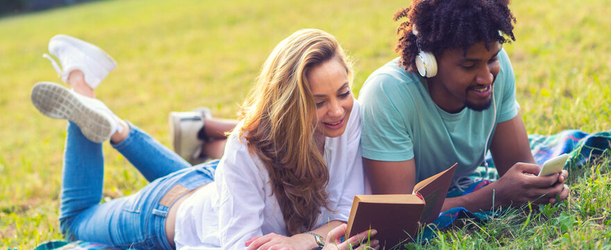 Young smiling couple lying on the meadow grass on a sunny summer day