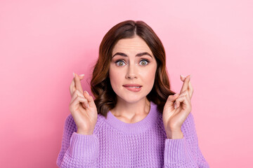 Photo of nervous worried woman with wavy hairstyle wear knit sweater fingers crossed biting lips isolated on pink color background
