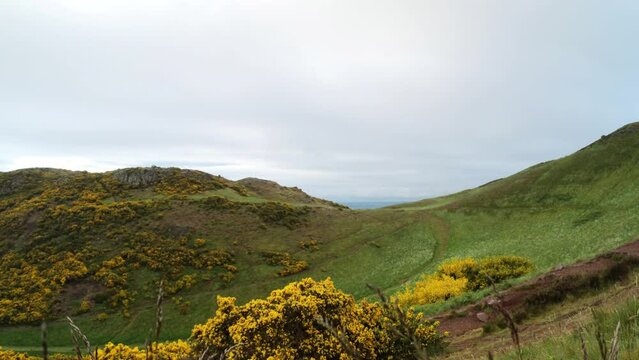 EDINBURGH, SCOTLAND, UK - MAY 31, 2022: Wide view on path between two peaks, Arthur's Seat ancient volcano on cloudy morning in Edinburgh, UK. 4k, Contains binaural audio