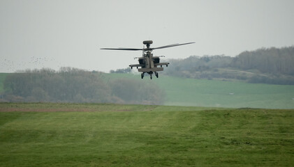 Fototapeta na wymiar dark grey helicopter hovering low above a field