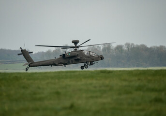 British army Boeing Apache Attack helicopter (AH-64E ZM722 ArmyAir606) hovers just above a grass meadow, Wiltshire UK