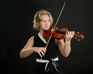 Sewickley, PA - JUNE 15TH 2022: a beautiful 16-year-old girl with fair skin and short blond hair is posing for studio portraits with her violin made by the string instruments maker.