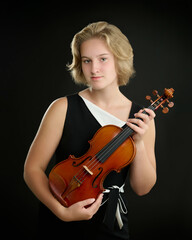 Sewickley, PA - JUNE 15TH 2022: a beautiful 16-year-old girl with fair skin and short blond hair is posing for studio portraits with her violin made by the string instruments maker.