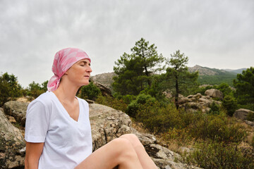 Woman with cancer closes her eyes while meditating and feels nature.