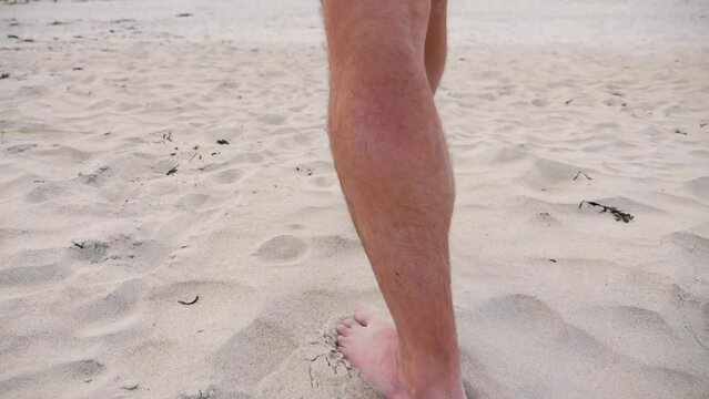 Man walking on beach feet in sand.