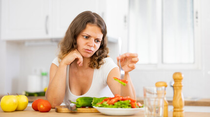 Portrait of disappointed young woman cooking at home kitchen