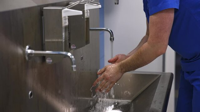Surgeon washing hands carefully preparing for operation. Unrecognized doctor getting ready for surgery in the preoperational room.