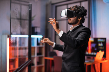 Young male company workers wearing VR headset while having meeting at office room. Confident bearded man in formal wear using innovative technology during business strategy.