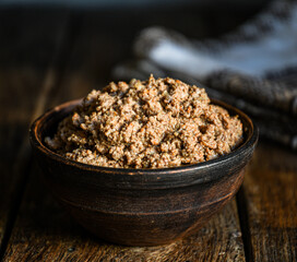 Homemade chicken liver pate in a ceramic dish on a wooden background.