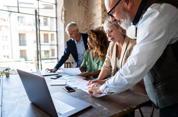 A team of middle-aged professionals are huddled around a conference room table, deeply engrossed in analyzing the data from a marketing campaign they designed for their top client