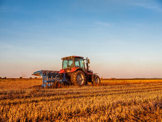 Obraz premium Farmer in tractor cultivating stubble field in preparation for seeding