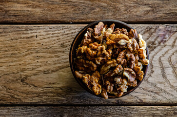 Peeled walnuts in an earthenware dish on a kitchen wooden table