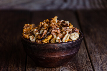 Peeled walnuts in an earthenware dish on a kitchen wooden table